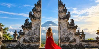 Ultimate Bali Travel Guide Woman in a red dress walking through Lempuyang’s split stone gates toward Mount Agung, East Bali